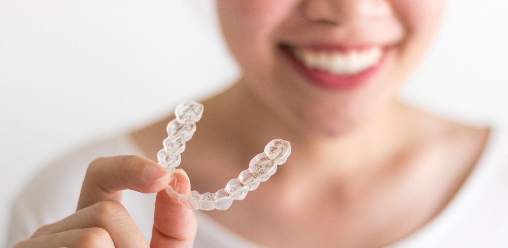 A smiling woman holding invisalign or invisible braces orthodontic equipment jpg