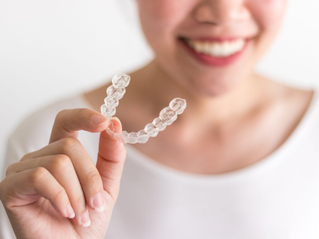 A smiling woman holding invisalign or invisible braces orthodontic equipment jpg