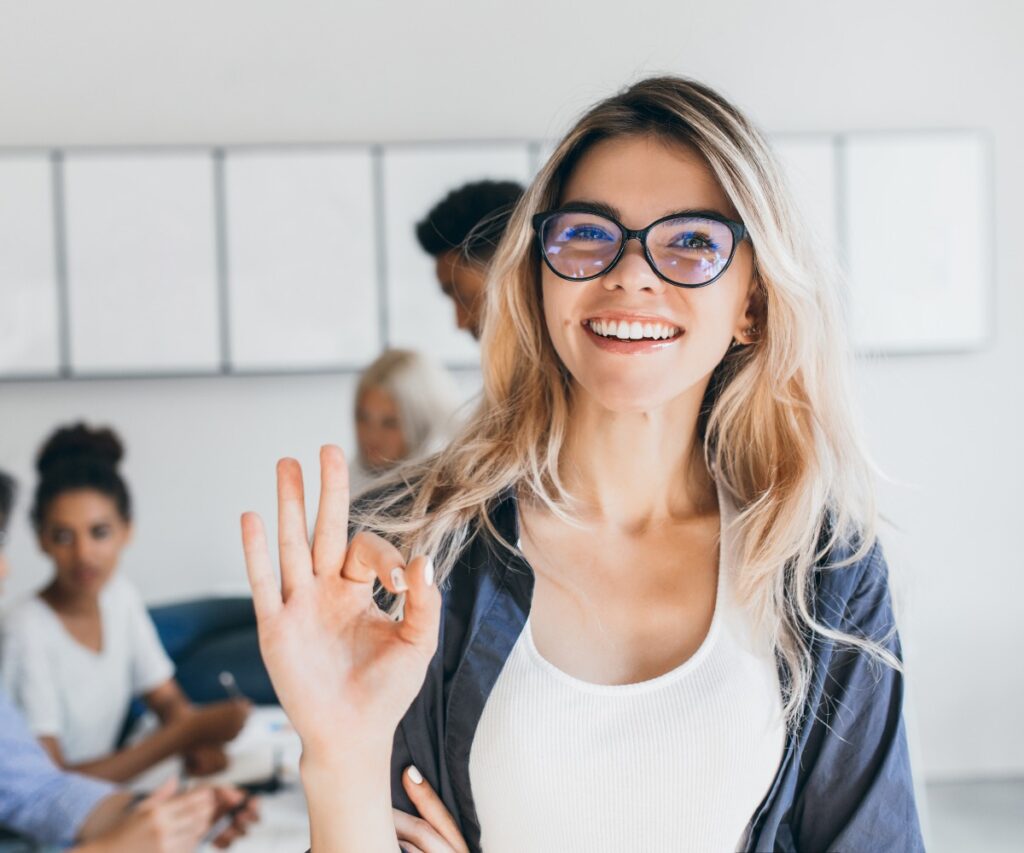 Close up portrait of pretty female manager from sales department indoor photo of smiling girl working in office with discussing people on background jpg