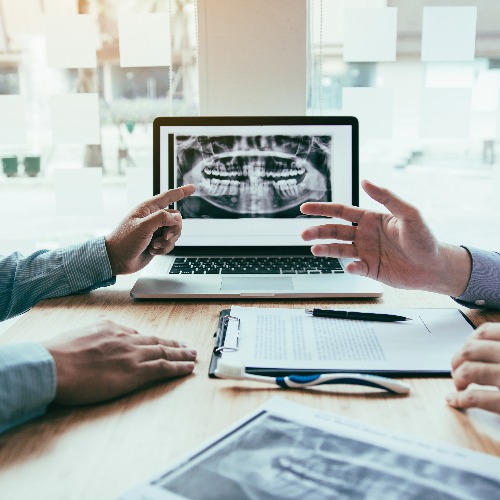 Dentist hand pointing x ray picture in laptop computer and talking to the patient about medication and surgery treatment jpg