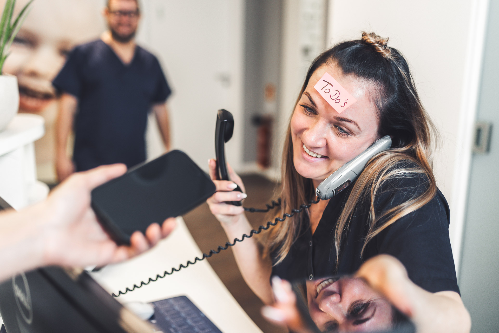 Eine lächelnde Frau telefoniert und hält einen Computer, mit "Tools" auf der Stirn.